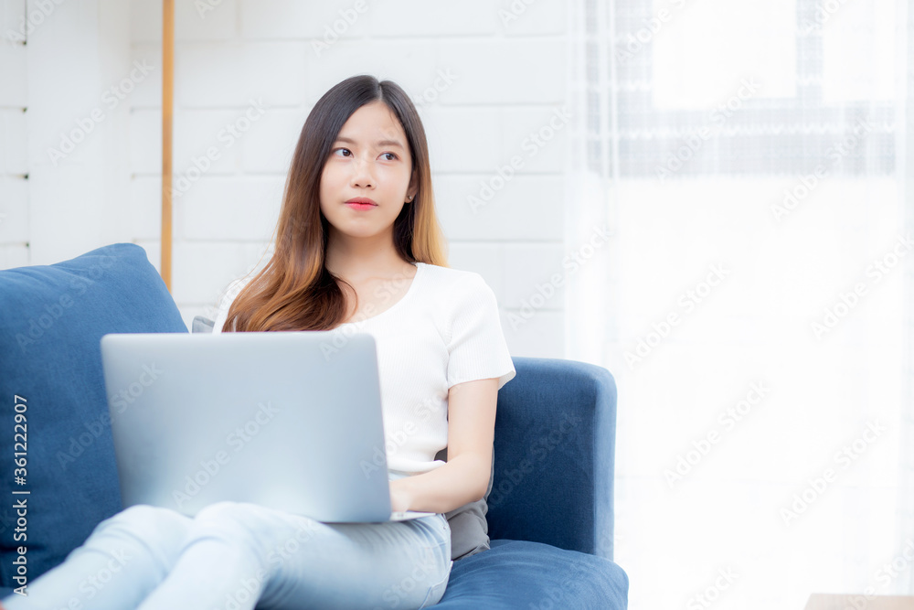 Young asian business woman smile and work from home with laptop computer online to internet on sofa in living room, freelance girl using notebook on couch with comfort, new normal, lifestyle concept. Young asian business woman smile and work from home with laptop computer online to internet on sofa in living room, freelance girl using notebook on couch with comfort, new normal, lifestyle concept.