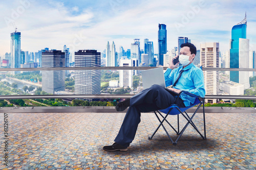 Businessman wear mask while work at office rooftop