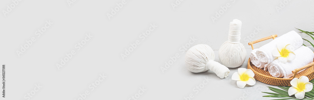 Spa massage Aromatherapy body care background. Spa herbal balls, cosmetics, towel and tropical leaves on gray concrete table. Web banner with copy space. Beauty and health care concept Spa massage Aromatherapy body care background. Spa herbal balls, cosmetics, towel and tropical leaves on gray concrete table. Web banner with copy space. Beauty and health care concept