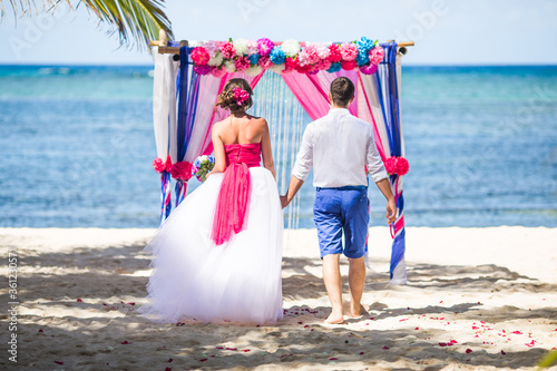 Fotografia Wedding newlyweds couple on the beach during destination wedding matrimonial marriage ceremony in Dominican, Punta Cana, tropical caribbean landscape with blue sea and sky