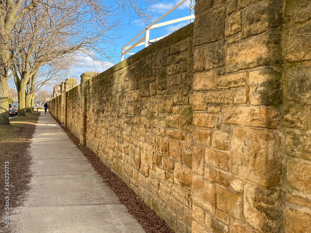 old stone wall with a blue sky lady walking