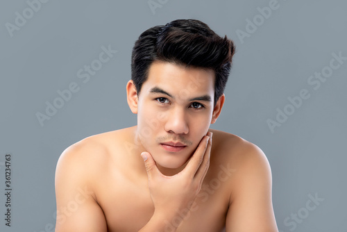 Portrait of shirtless young handsome Asian man for skincare and beauty concepts against gray studio background