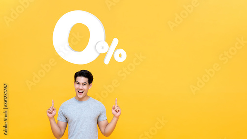 Young handsome Asian man pointing up to 0% on yellow background with copy space for no interest installment payment concept