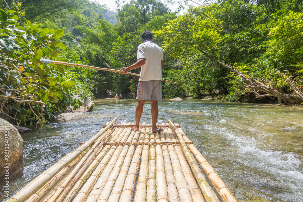 Phuket, Thailand - July 10, 2014. Man standing on bamboo raft and looking out Phuket, Thailand - July 10, 2014. Man standing on bamboo raft and looking out