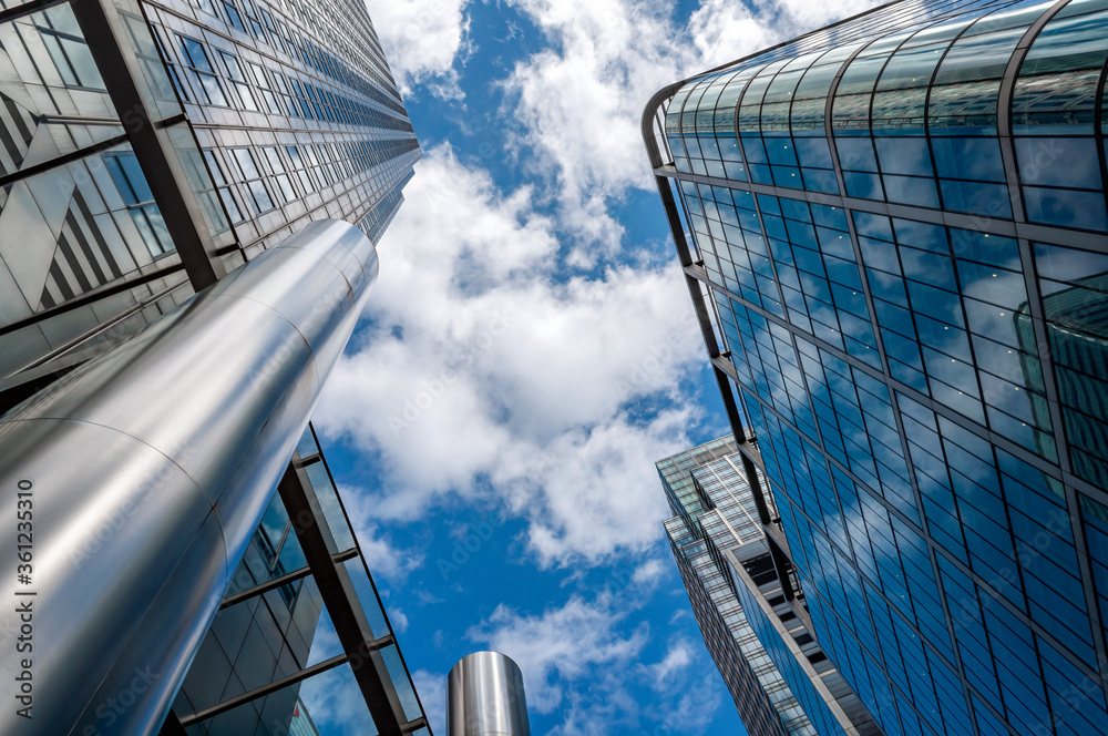 Corporate buildings, business district and financial district concept with photograph of upward view of generic skyscrapers against clouds and the blue sky