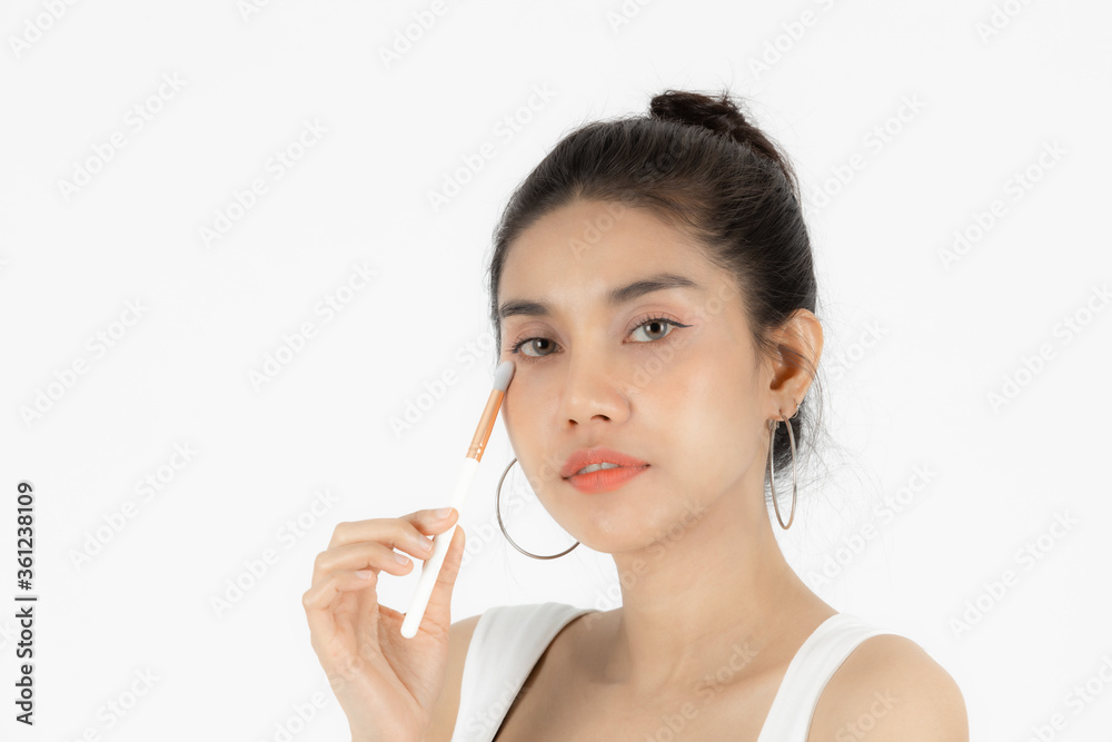 Healthy and cosmetics concept. Beauty face of young Asian woman applying make up with brush over white isolated background. Healthy and cosmetics concept. Beauty face of young Asian woman applying make up with brush over white isolated background.