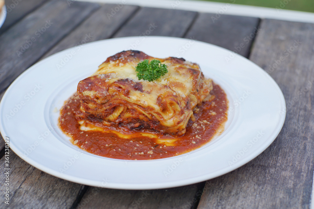 Close up of meat lasagna on a white plate with wooden table background. Close up of meat lasagna on a white plate with wooden table background.