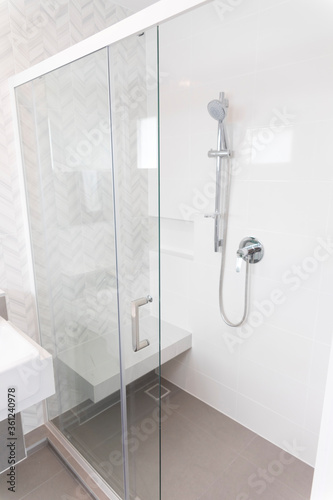 Shower room with chrome tap  transparent glass doors and a shelf. Apartment or hotel room. 