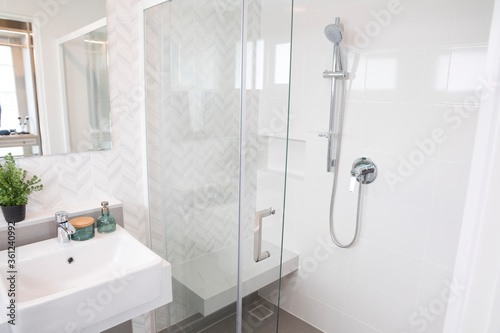Shower room with chrome tap  transparent glass doors and a shelf. Apartment or hotel room. 