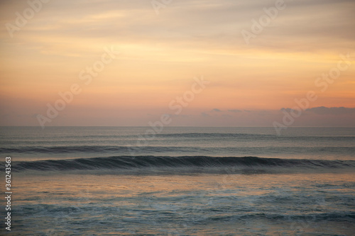 Calming sunset on the beach of  Pantai Lima with isolated glassy ocean wave, Bali Indonesia. 