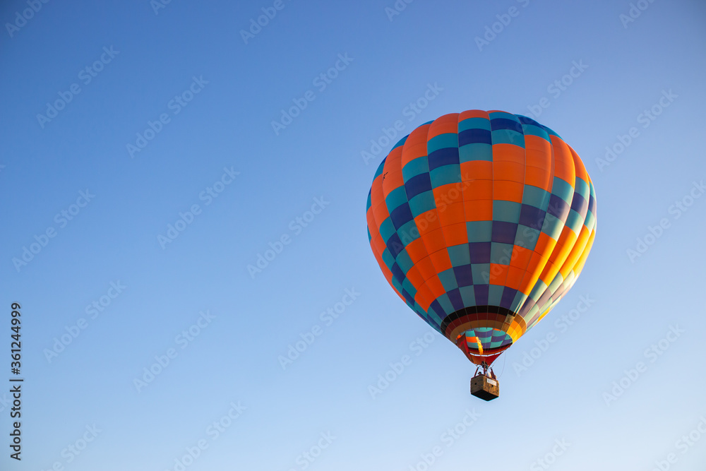Fototapeta premium Kyiv, Ukraine - 06/26/2020: Hot air balloon in clear summer sky. Colorful balloon on blue background. Bright geometric design. Summer adventure and leisure. Aviation sport concept.