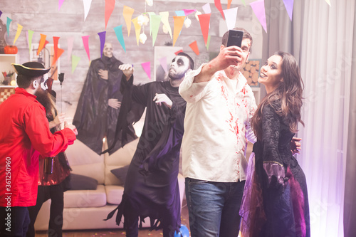 Cheerful man and woman dressed up like a witch and zombie for halloween party.