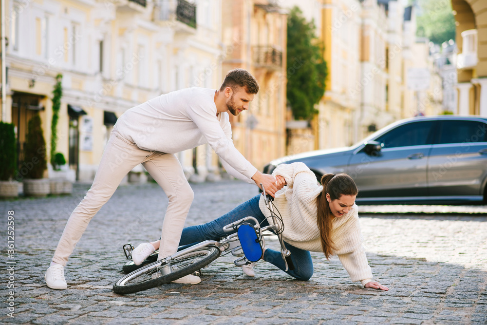 Man helping woman with bicycle to climb on street