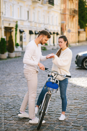 Man examining arm womans standing with bicycle