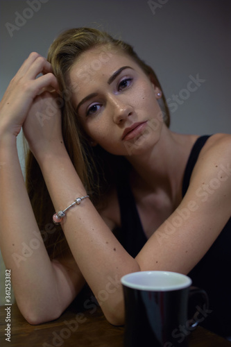 Girl in grey suit posing in cafe with cup of coffee