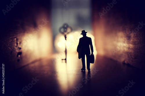 concept image of person walking towards bright light and finding the right key in dark path