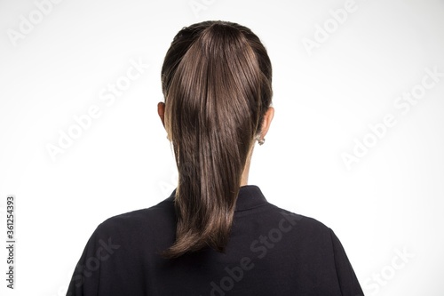 Back view of a female dark brown straight hair ponytail small earrings black shirt white background