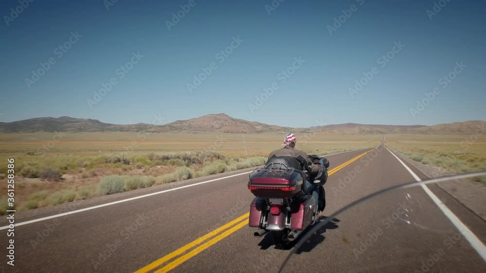Motorcycle filmed from behind while riding on an american highway in the desert sun of California Motorcycle filmed from behind while riding on an american highway in the desert sun of California