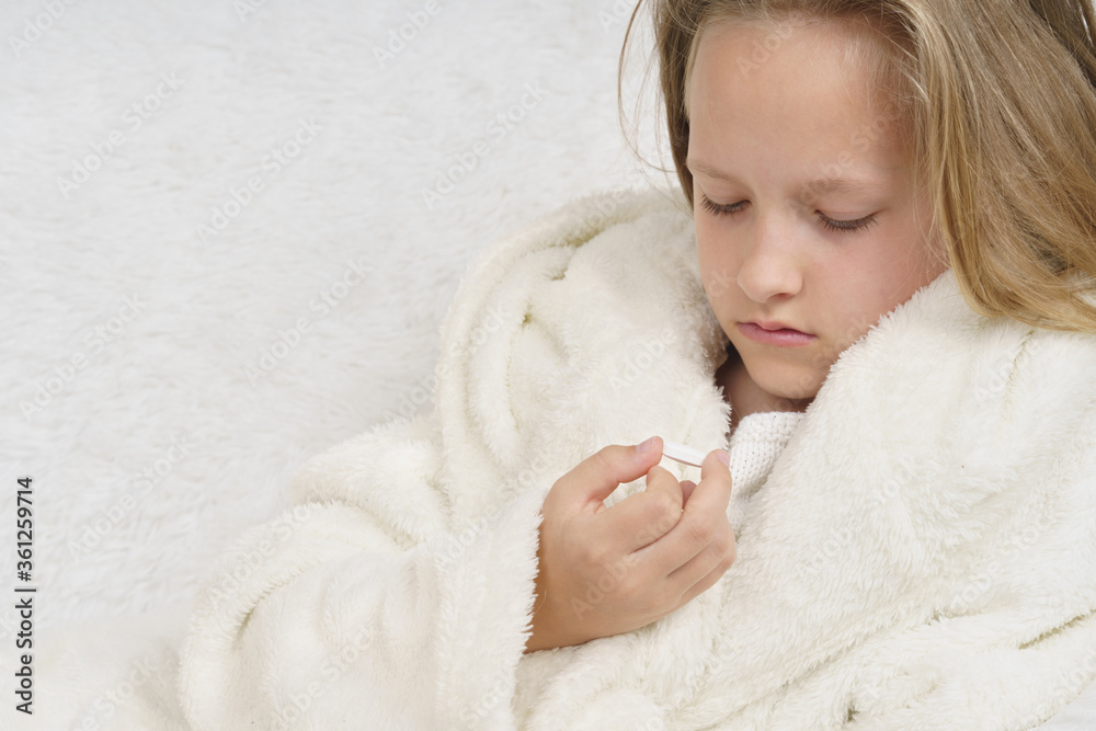 A girl takes a thermometer from the table where the medicines are. A girl takes a thermometer from the table where the medicines are.