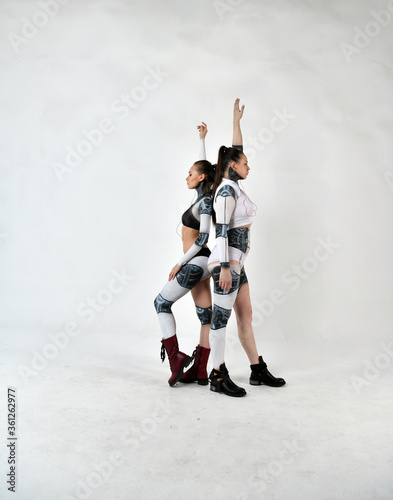 beautiful and warlike girls in robotic costumes as sisters are ready to protect each other