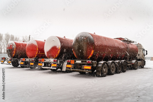 Oil truck with tank trailers in a winter parking lot in a blizzard. Photo taken in Russia