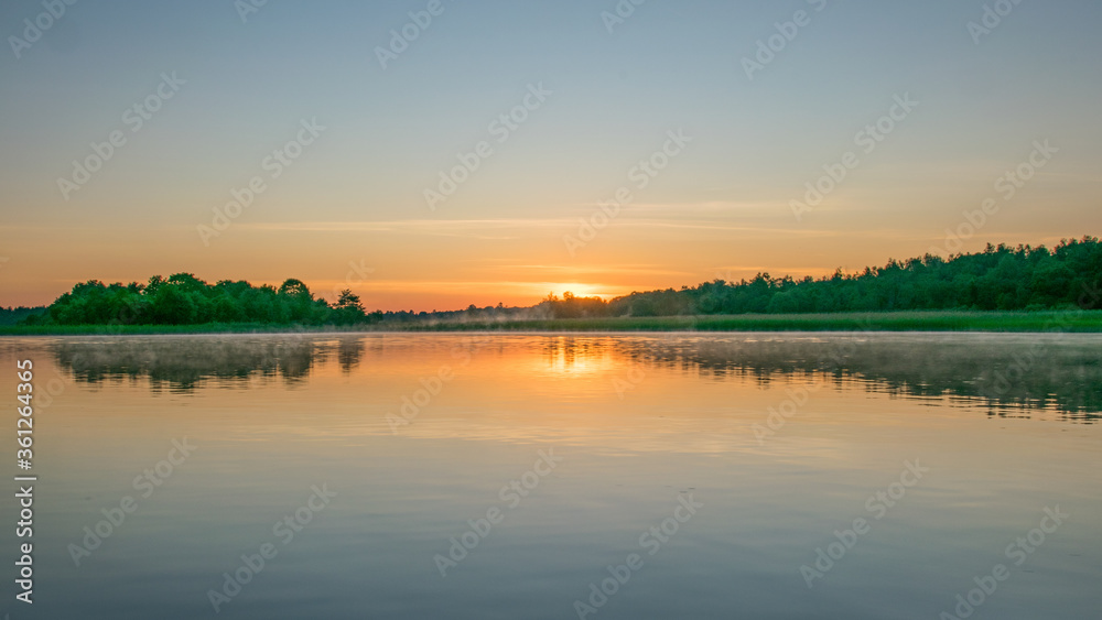 Fototapeta premium Foggy weather early in the morning on the lake. beautiful wallpapers. a mystical mist vibrates in the lake. summer sunrise