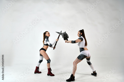 beautiful girls in costumes of robots quarreled and fight with a battle ax and a war hammer