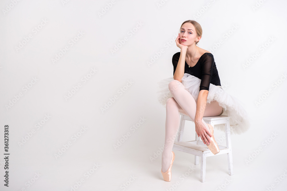 Fototapeta premium Young beautiful ballerina dances in big studio and poses for the camera isolated on white background