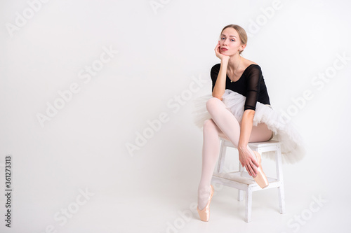 Young beautiful ballerina dances in big studio and poses for the camera isolated on white background