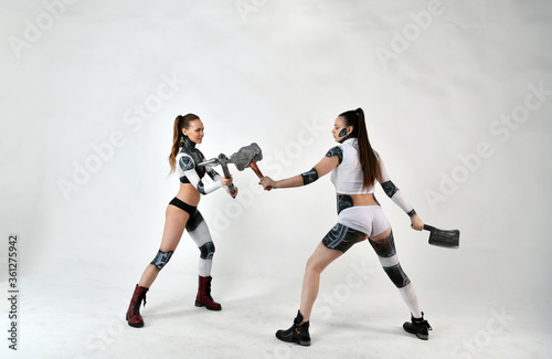 beautiful girls in costumes of robots quarreled and fight with a battle ax and a war hammer