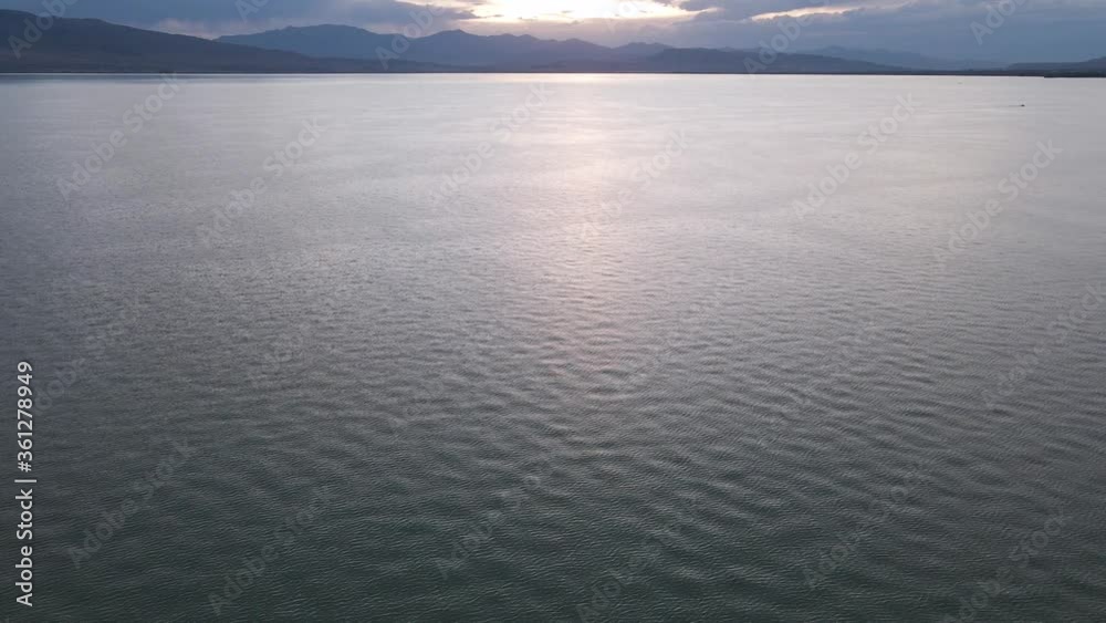 Sunset over lake with mountains backdrop, 4K aerial footage
