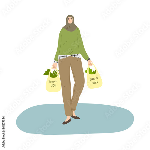 Young smiling muslim woman in hijab and casual clothing carrying shopping bags