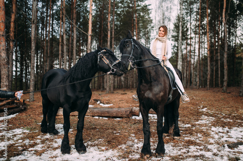 Elegant woman in a grey coat riding on a black horse