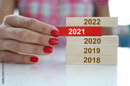 Female hand hold red wooden block with 2021 sign closeup. Chops and changes concept photo