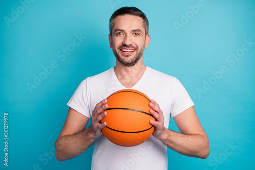 Close-up portrait of his he nice attractive sporty successful cheerful cheery bearded guy wearing tshirt playing basketball isolated over bright vivid shine vibrant blue color background