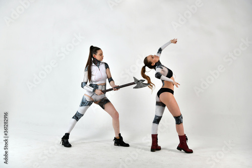 Fototapeta Naklejka Na Ścianę i Meble -  beautiful girls in costumes of robots quarreled and fight with a battle ax and a war hammer