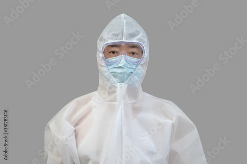 An Asian man wearing protective suit, medical masks, and goggles on a gray background.