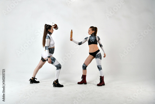 beautiful girls in costumes of robots quarreled and fight with a rolling pin and a big bottle