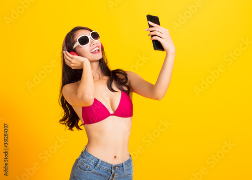 beautiful young woman wearing swimsuit bikini and watching smart phone