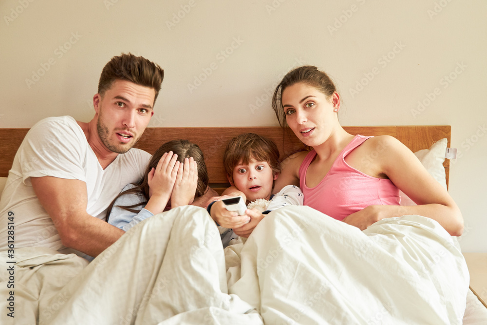 Parents and children in bed with remote control