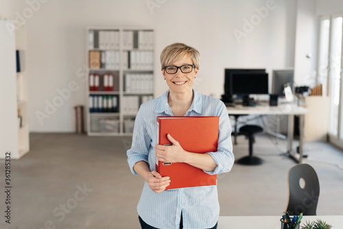 Billede på lærred Smiling happy businesswoman clutching a binder