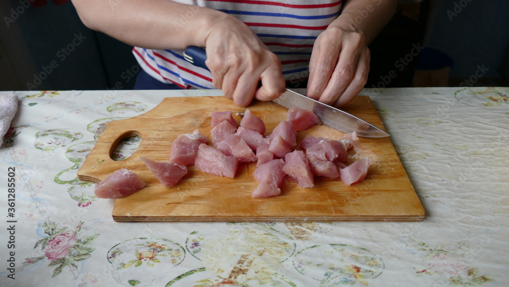 the cook cuts raw meat into pieces