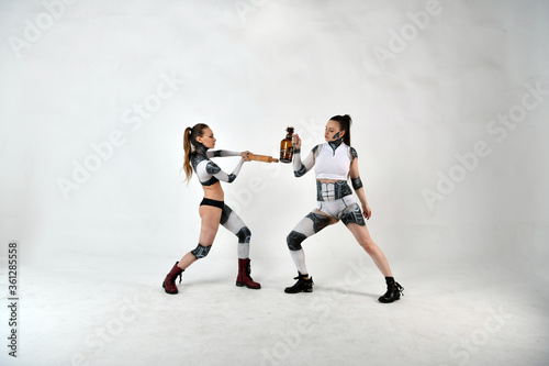 beautiful girls in costumes of robots quarreled and fight with a rolling pin and a big bottle