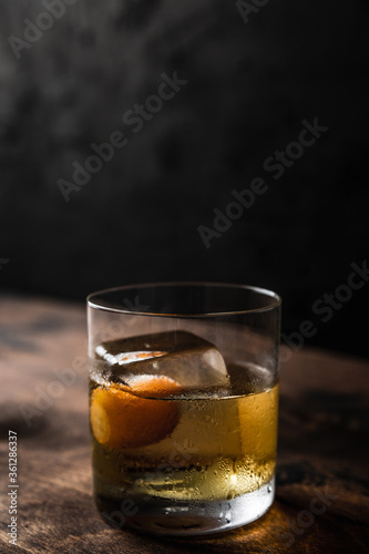Old fashioned cocktail in a rocks glass with a big ice cube, back light