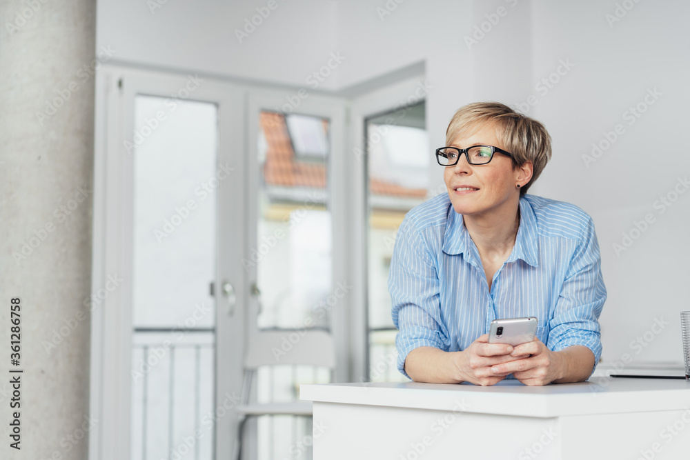 Woman standing leaning on a cabinet watching Woman standing leaning on a cabinet watching