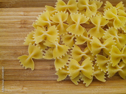 Pasta bows scattered on a wooden board.