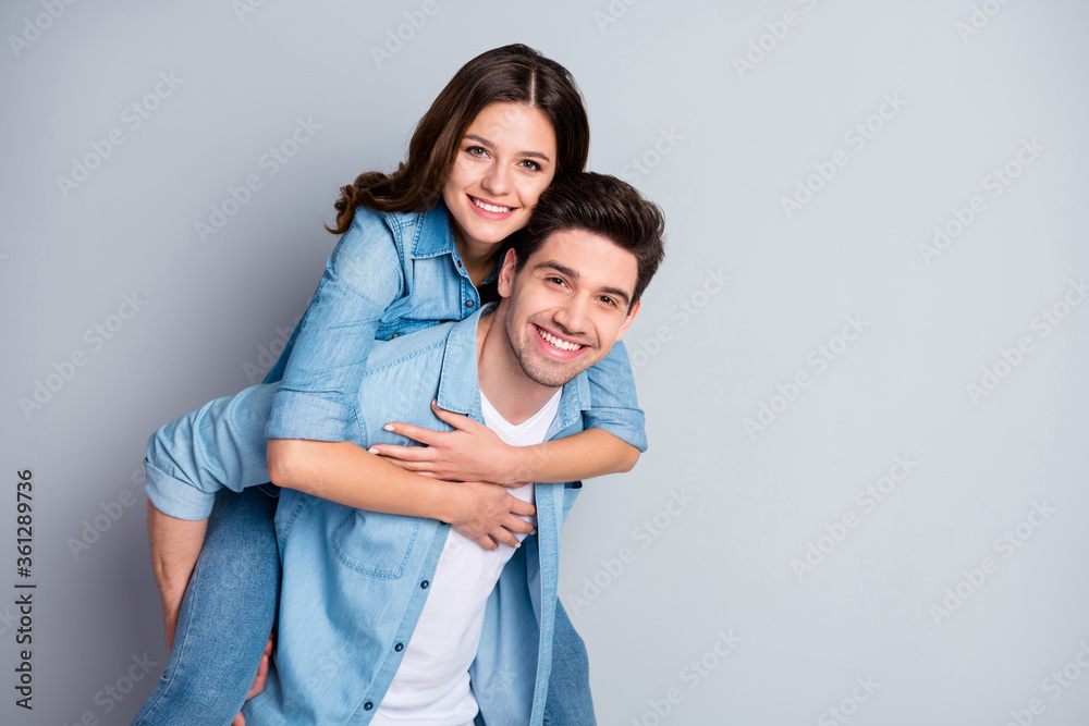 Portrait of positive passionate student spouses enjoy togetherness weekend hug piggyback wear jeans casual style outfit isolated over gray color background Portrait of positive passionate student spouses enjoy togetherness weekend hug piggyback wear jeans casual style outfit isolated over gray color background
