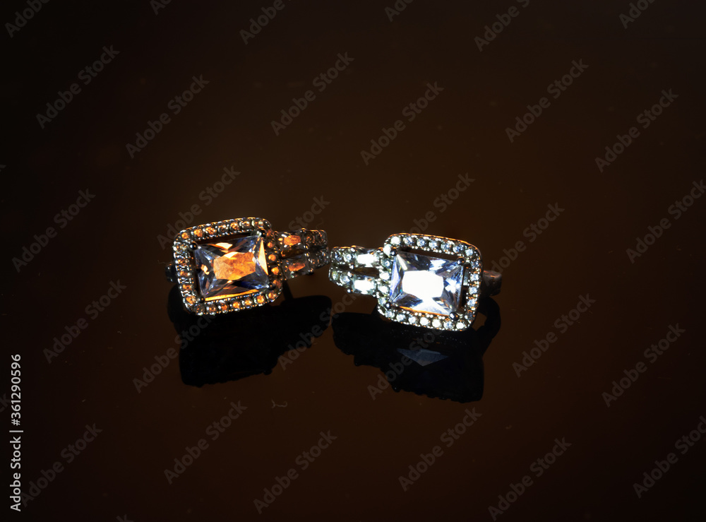 Jewelry, diamond earrings close-up on a dark background. Jewelry, diamond earrings close-up on a dark background.