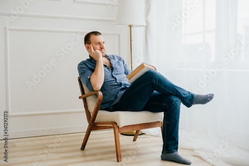 Beautiful mansits on a chair with a book in big bright room