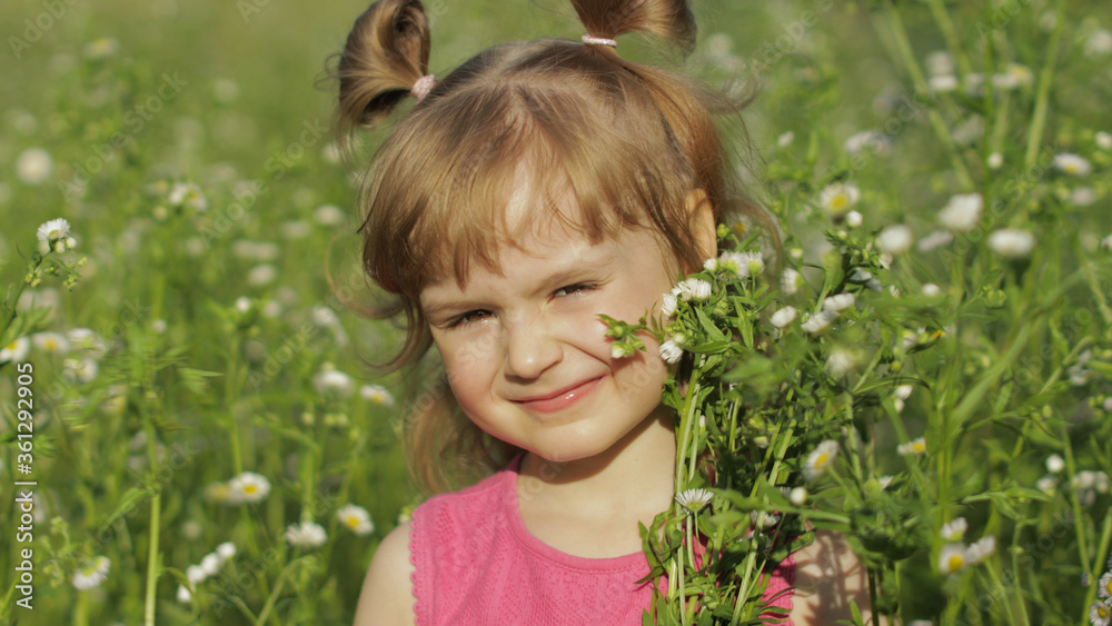 Little blonde child girl in pink dress stay on flower chamomile grass meadow. Bouquet of daisies Little blonde child girl in pink dress stay on flower chamomile grass meadow. Bouquet of daisies